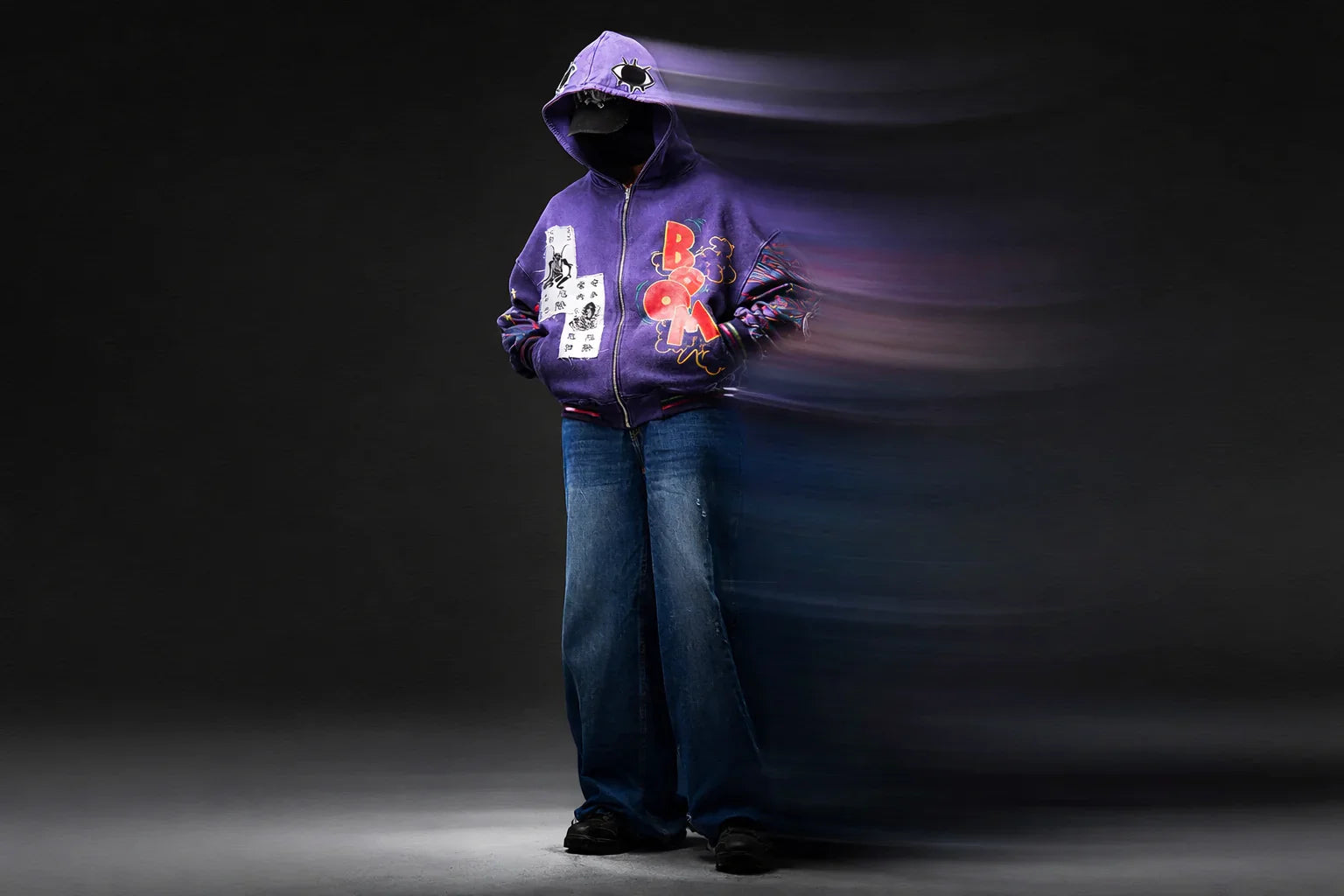 Purple graphic hoodie with bold prints, paired with wide-leg jeans, styled for modern streetwear fashion.