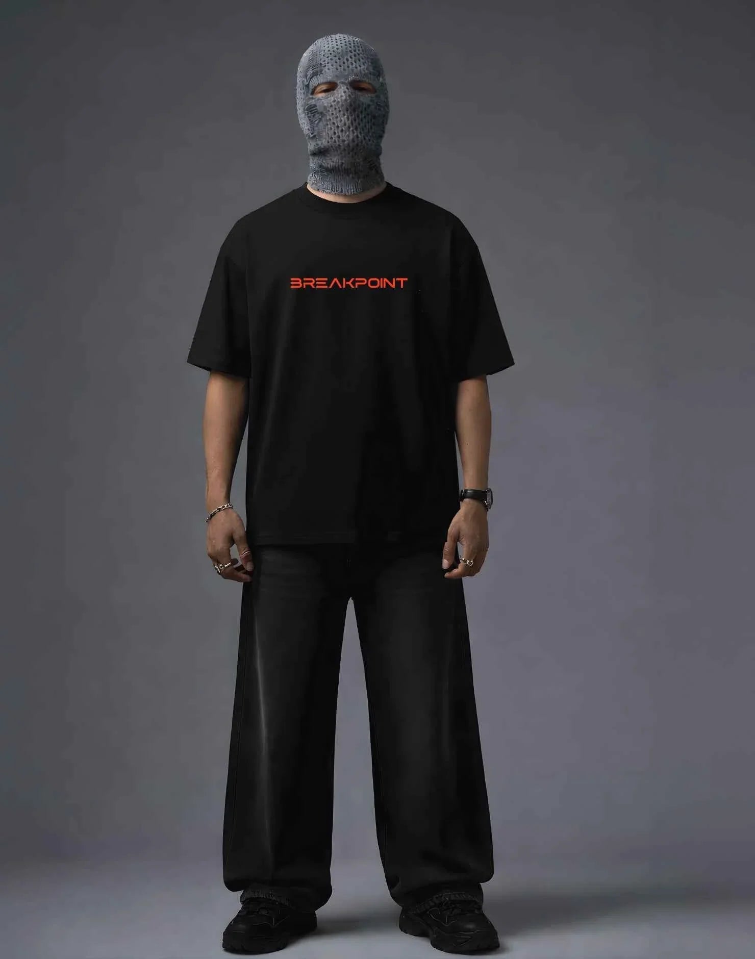 Black oversized t-shirt with red BREAKPOINT logo, paired with wide-leg pants and knit balaclava for streetwear style