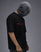 Black graphic tee with orange text, paired with textured gray face mask, modern streetwear style