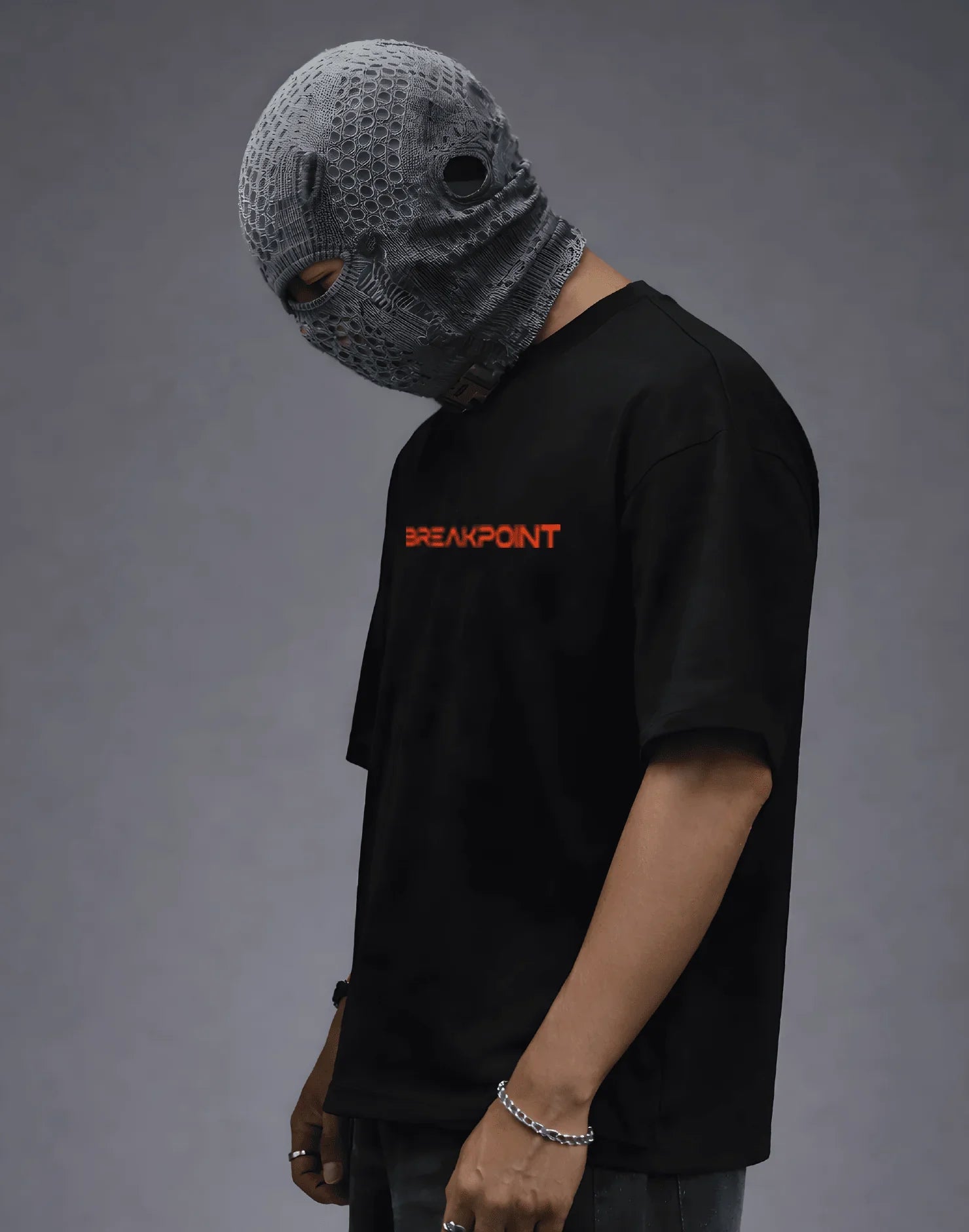 Black streetwear tee with orange 'BREAKPOINT' text, paired with textured gray balaclava, modern urban fashion