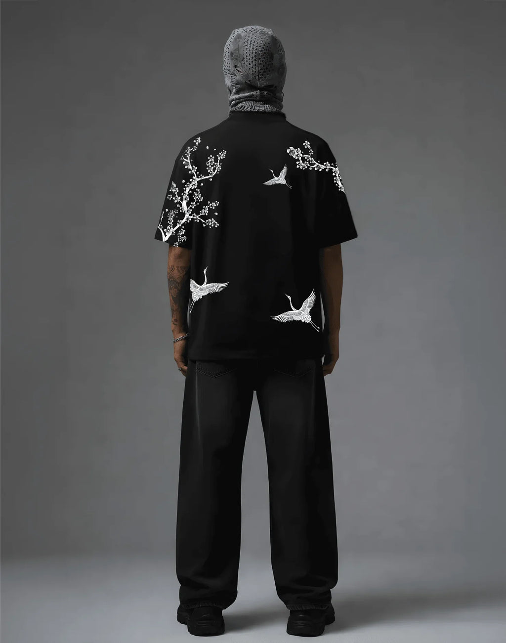 Black graphic tee with white crane and blossom print, streetwear style, back view