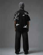 Black graphic tee with white crane and blossom print, streetwear style, back view