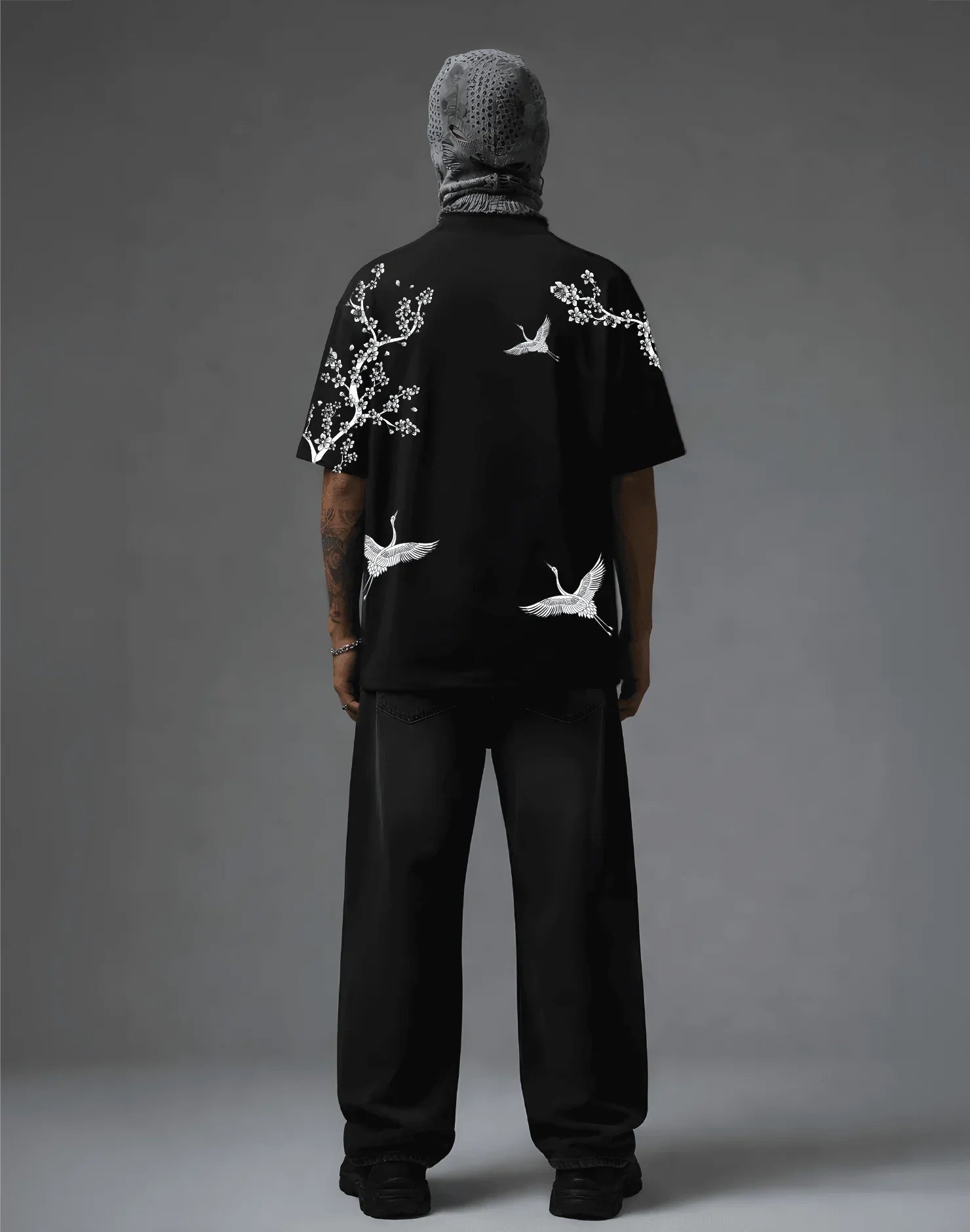 Black graphic tee with white crane and blossom print, streetwear style, back view