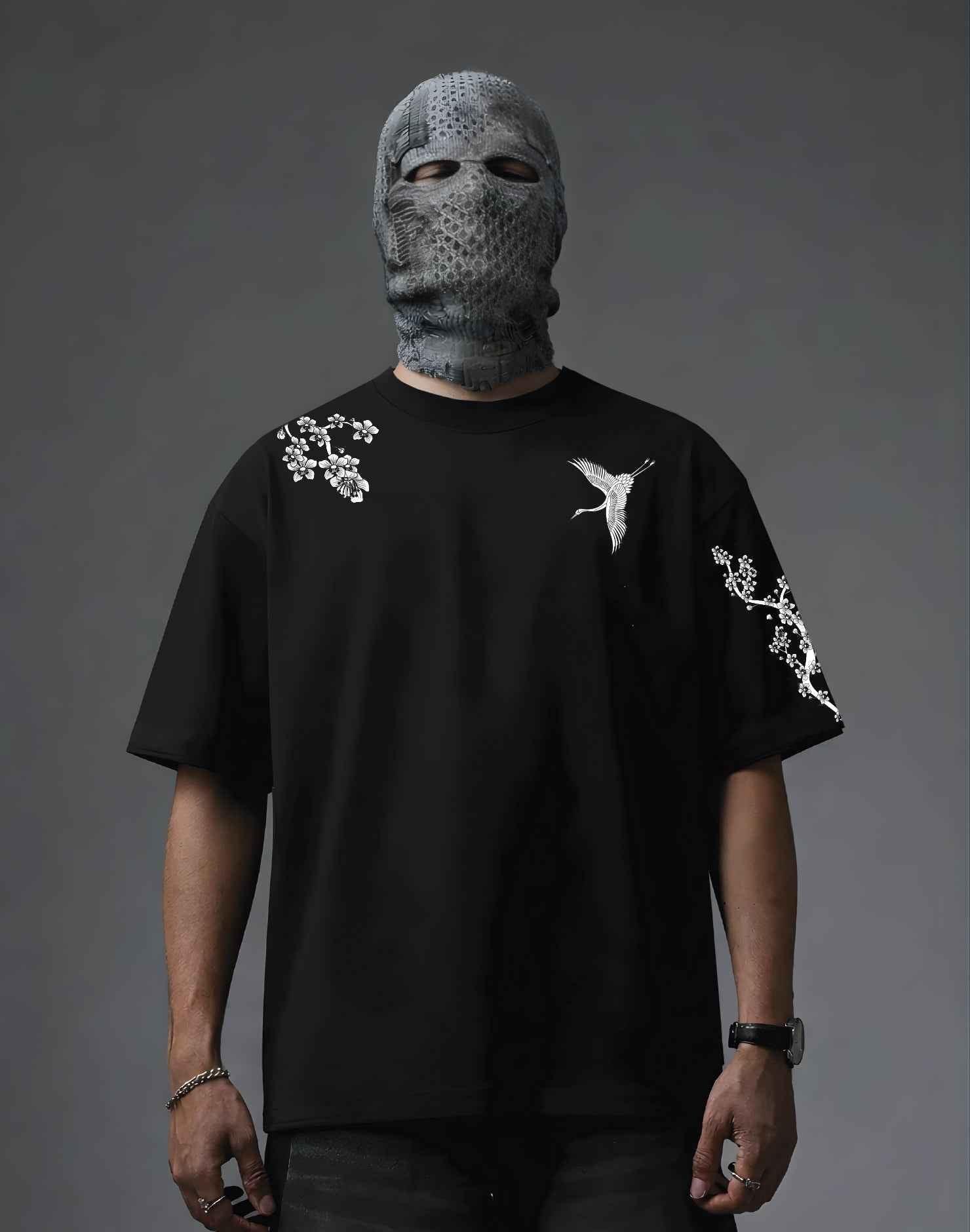 Black graphic tee with crane and cherry blossom print, worn with textured face mask for edgy streetwear style