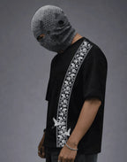 Black graphic tee with floral side stripe, paired with textured face mask for edgy streetwear style.